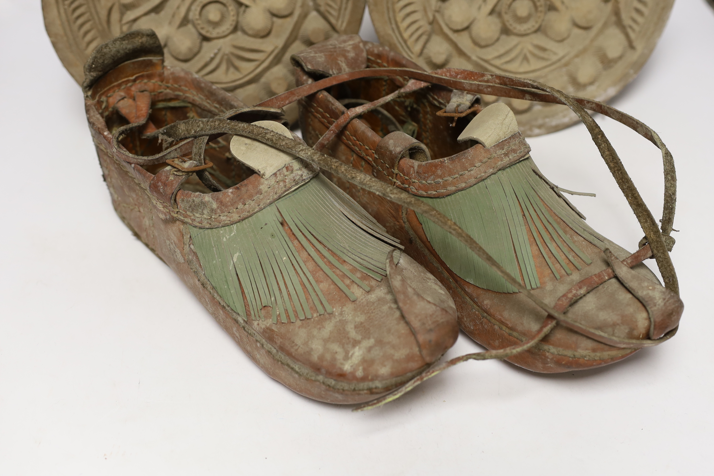 A pair of Spanish-Colonnial carved wood stirrups and a pair of Indian leather shoes